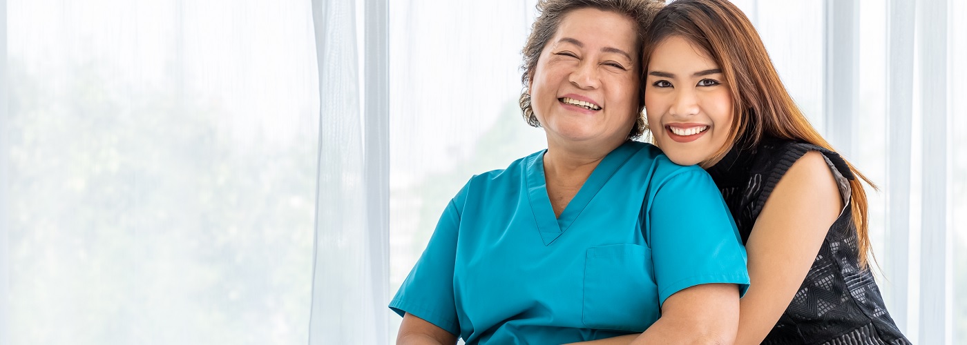 Smiling woman in scrubs with a patient