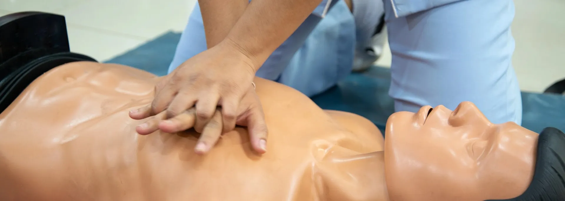 Person performing chest compressions on a CPR manikin during a training session