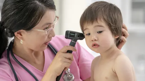 An ENT specialist examining a young child's ear