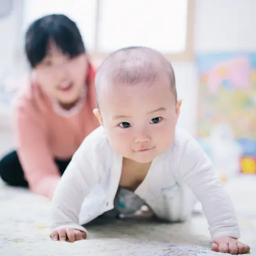 A healthy baby crawling on the floor with mother