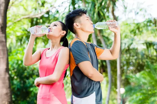 Man and woman drinking water outdoors to support kidney and urinary health
